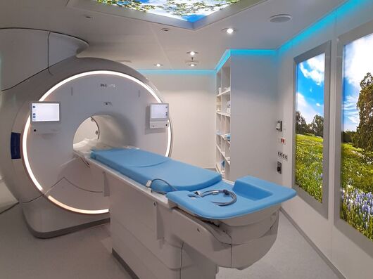 Ein CT-Gerät- An der Decke und an der Wand ist ein Foto vom Himmel bzw. einer Landschaft zu sehen