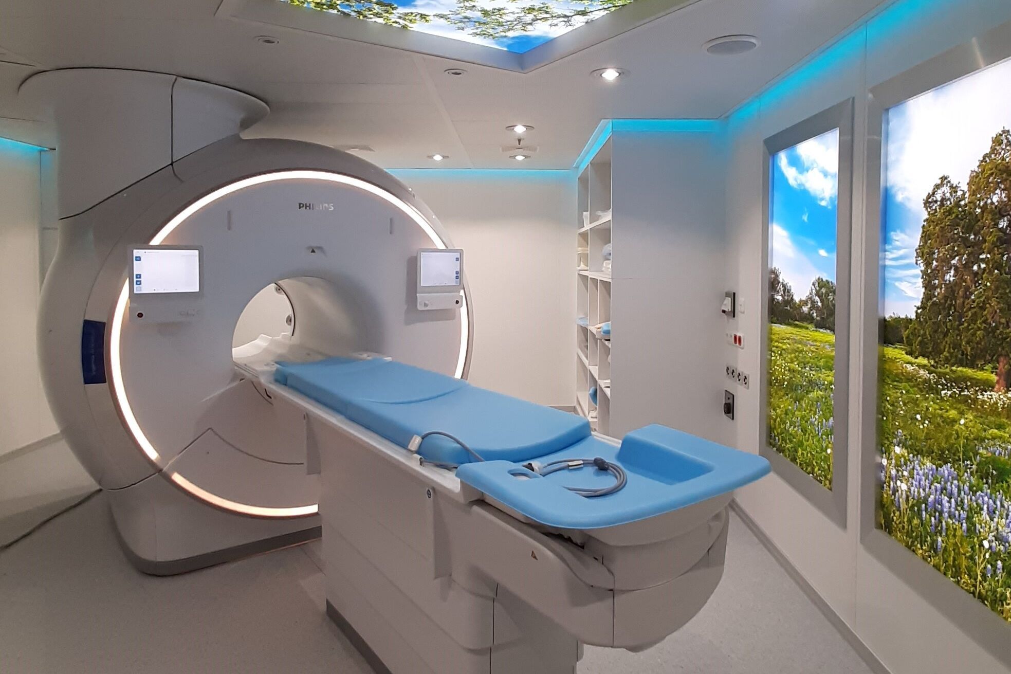 Ein CT-Gerät- An der Decke und an der Wand ist ein Foto vom Himmel bzw. einer Landschaft zu sehen