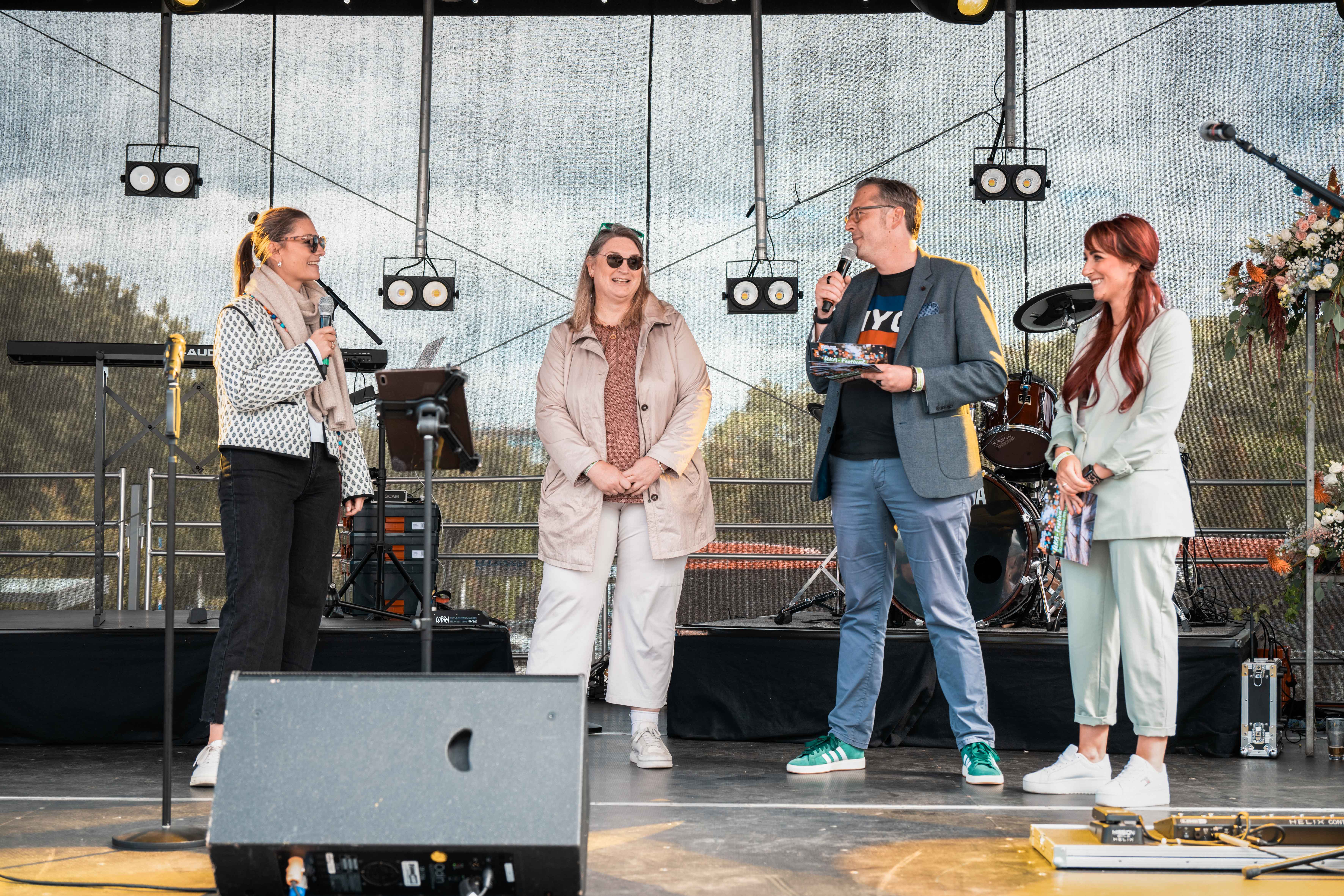 Ein Moderator und eine Moderatorin interviewen zwei Frauen auf einer Bühne.