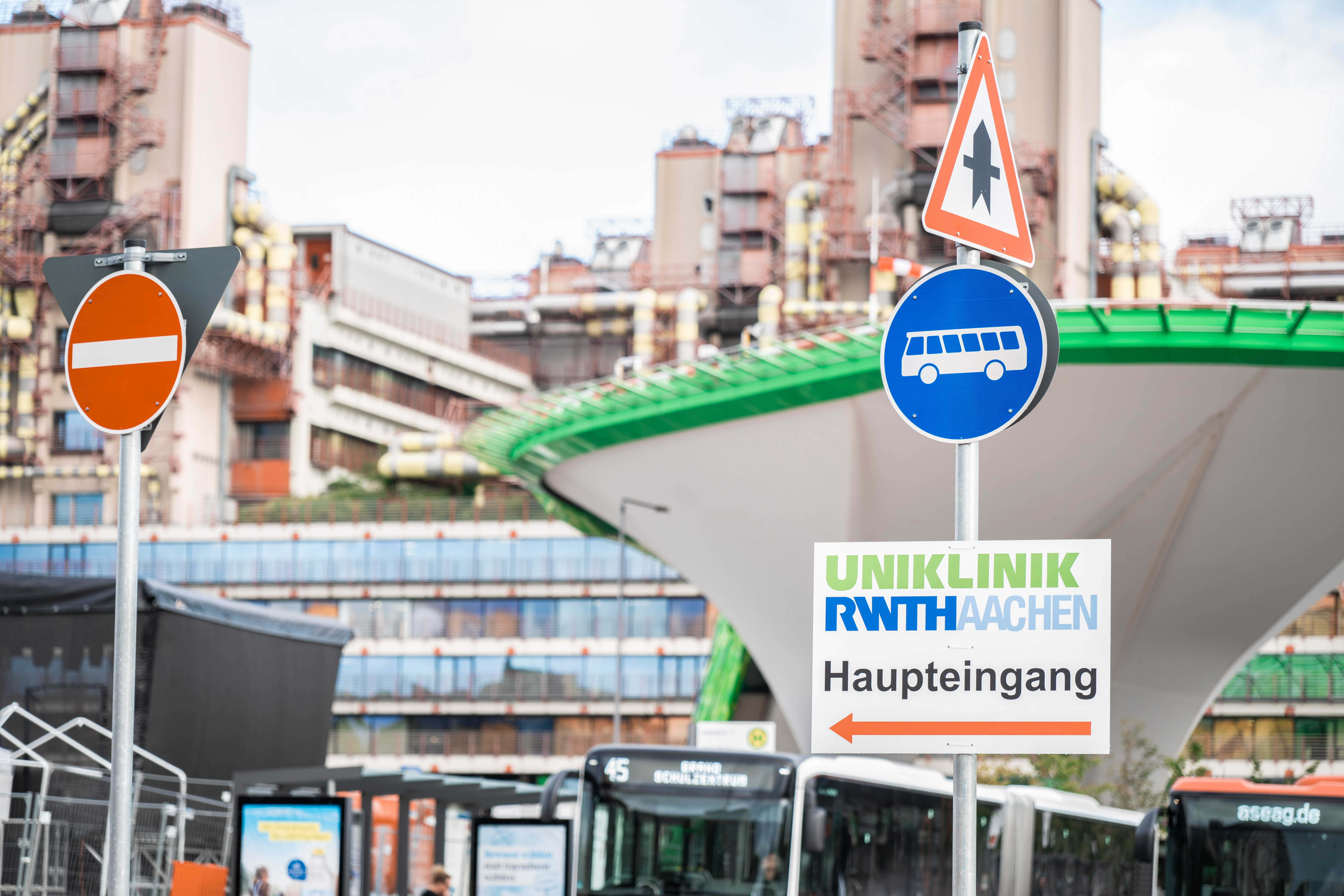 Das Bild zeigt Straßenschilder vor der Uniklinik RWTH Aachen, auf einem Schild steht Uniklinik RWTH Aachen mit einem roten Pfeil nach links.