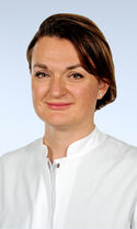 Eine Frau mittleren Alters mit braunen Haaren und akkurater Frisur, die freundlich in die Kamera guckt.