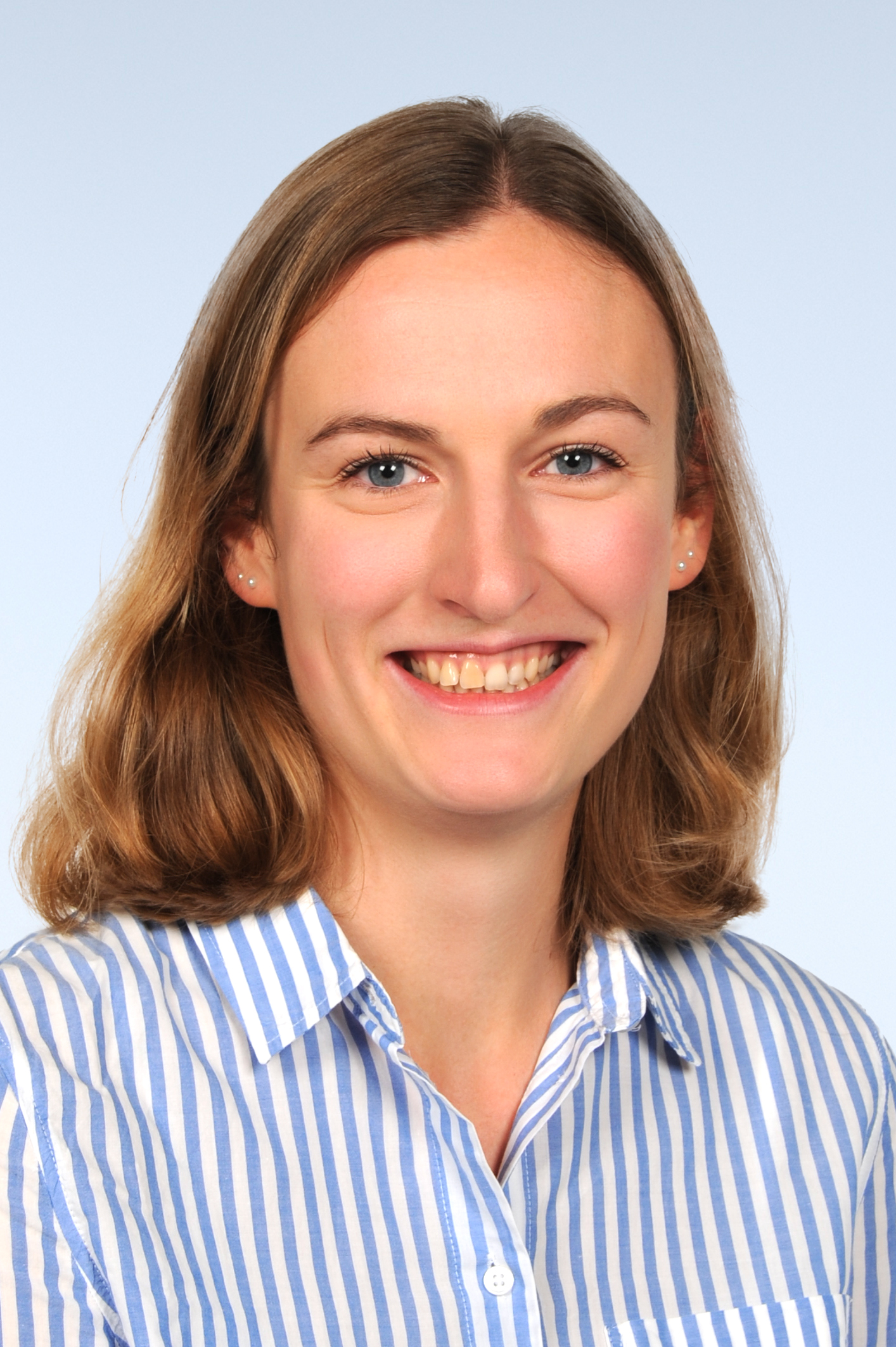 Portrait von Frau mit schulterlangen hellbraunen Haaren. Sie lacht in die Kamera und trägt eine blau-weiß-gestreifte Bluse.