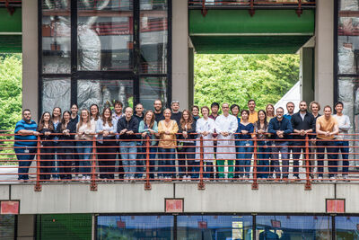 Gruppenfoto von vielen Personen, die an einem Geländer stehen und in die Kamera schauen