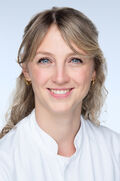 Porträtfoto einer Frau mit dunkelblonden gewellten Haaren. Sie lächelt freundlich in die Kamera.
