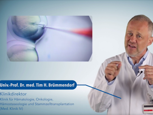 Das Bild zeigt einen Mann mit gräulichen Haaren in einem weißen Arztkittel und einem medizinischen Bild.