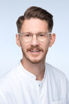 Priv.-Doz. Dr. Dr. med. Ben Arpad Kappel Porträtfoto eines Mannes mit dunklem Haar und runder Brille, der einen weißen Kittel trägt und freundlich in die Kamera schaut.