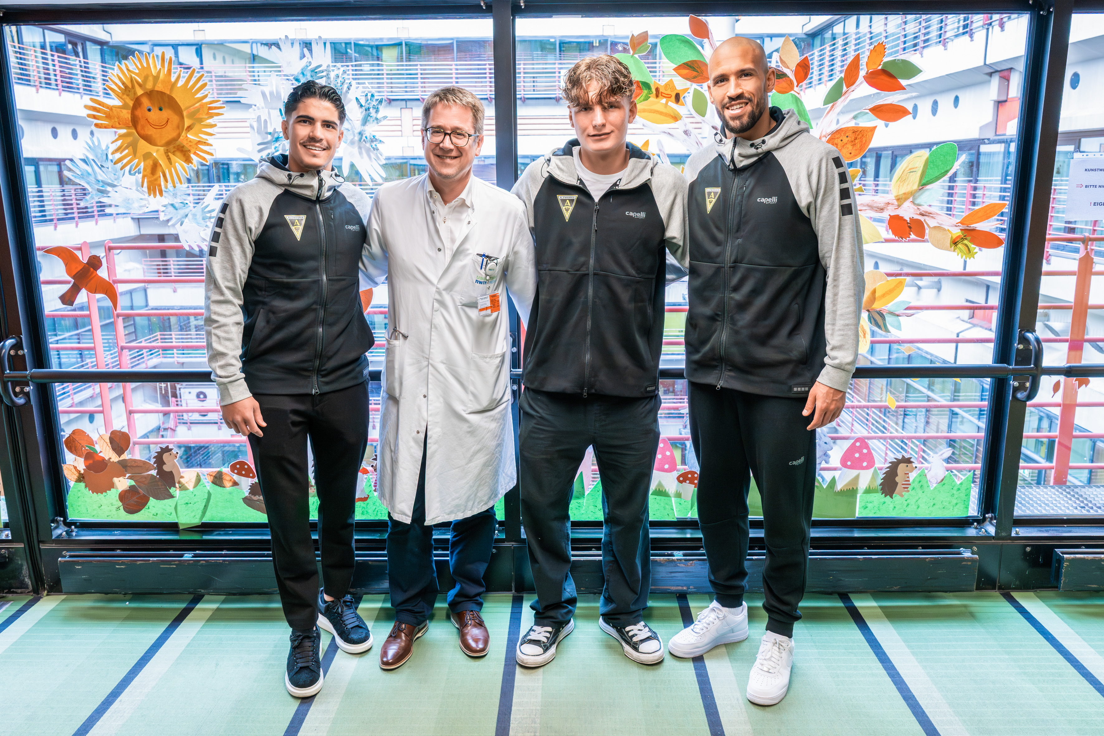 Gruppenfoto mit den drei Fußballern von Alemannia mit dem Klinikdirektor der Kinder- und Jugendmedizin 