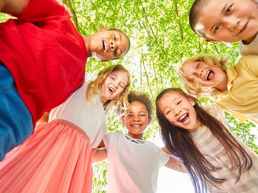 Kinder stehen im Kreis und lachen (im Wald)