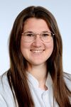 Frau mit schulterlangen, braunen Haaren und einer Brille. Sie lächelt freundlich in die Kamera. 