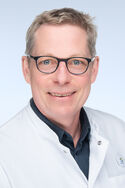 Univ.-Prof. Dr. med. Hans Clusmann Mann mir Brille im weißen Kittel der freundlich in die Kamera schaut.