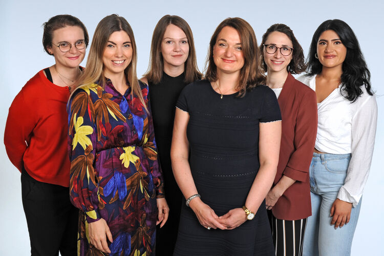 Sechs Frauen, die zusammen in die Kamera lächeln