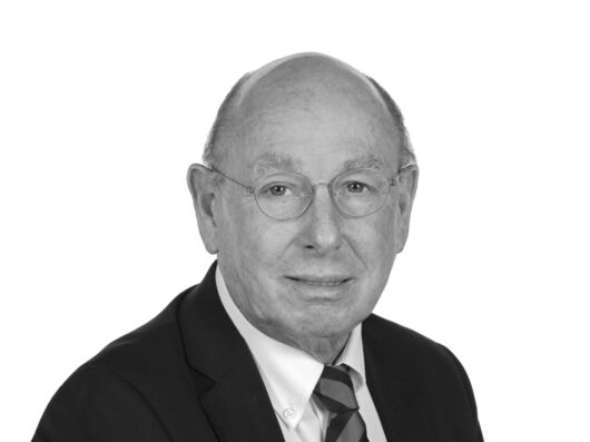 Porträtfoto eines Mannes mit hoher Stirn und einer dünnen Brille. Er trägt ein weißes Hemd, eine Krawatte und ein dunkles Sakko.