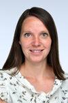 Frau mit schulterlangen, braunen Haaren. Sie lächelt freundlich in die Kamera.