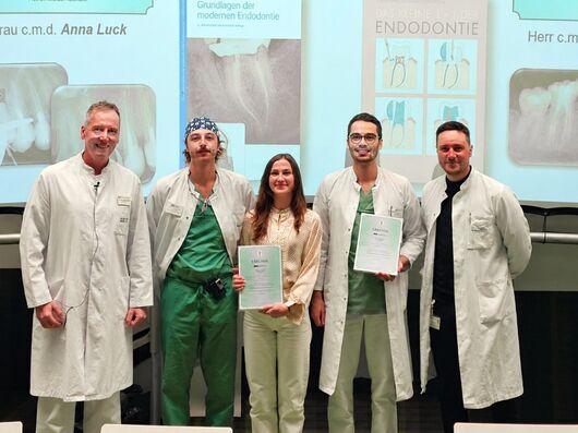 Überreichung der Urkunden der Fachzeitschrift „Endodontie“ an Anna Luck (Mitte) und Felix Buß-meier (2. von rechts) durch Klinikdirektor Univ.-Prof. Dr. Andreas Braun (links), Zahnarzt Dr. Tim Klomp (2. Von links) und Oberarzt Dr. Johannes-Simon Wenzler (rechts) haben die Studierenden im praktischen Kurs betreut.