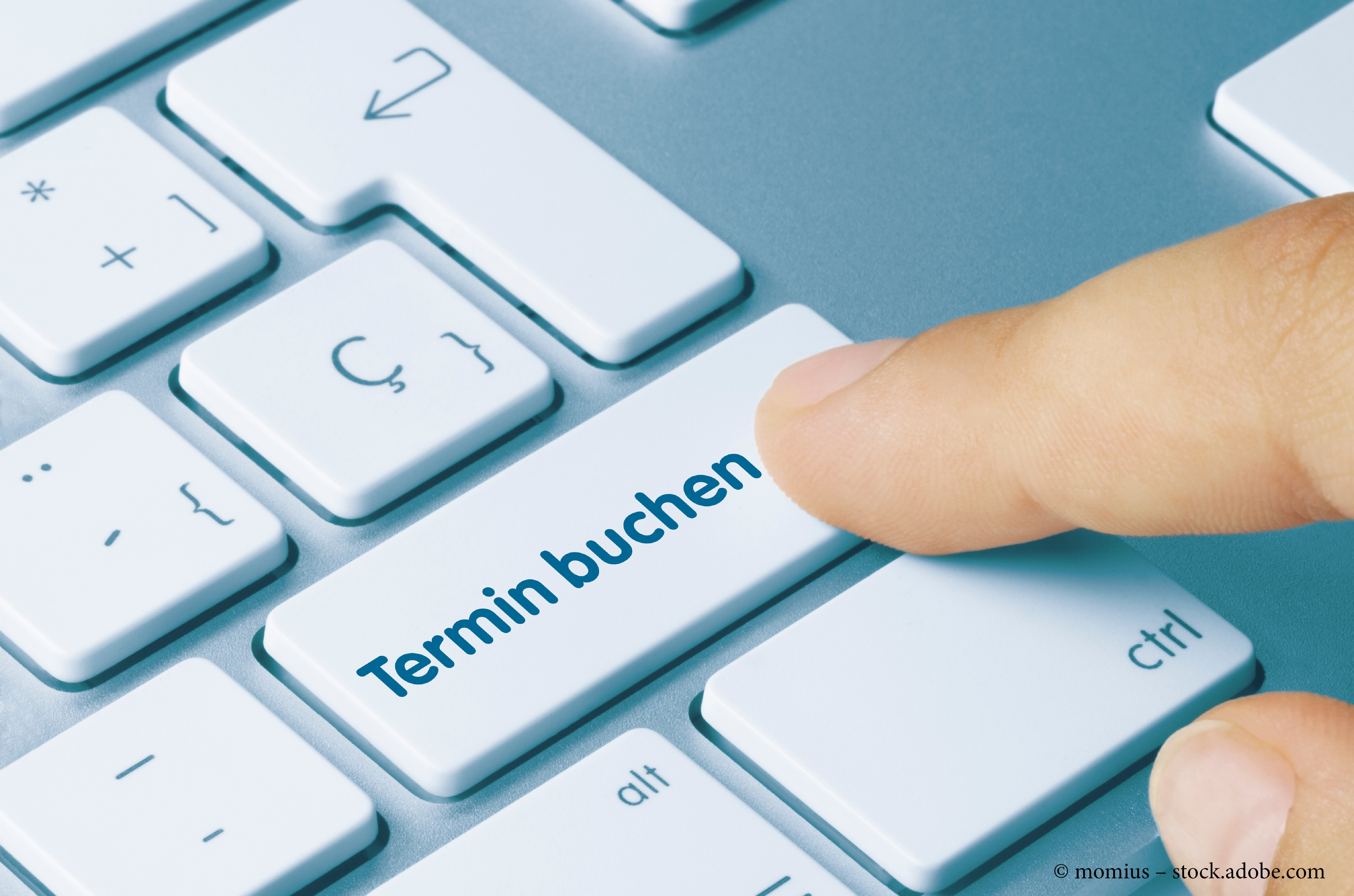 Finger, der auf eine Taste mit der Aufschrift "Termin buchen" auf einer Computertastatur drückt.