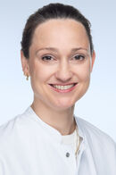 Portraitfoto einer Frau mit dunklen Haaren in einem weißen Kittel, die freundlich in die Kamera lächelt. 